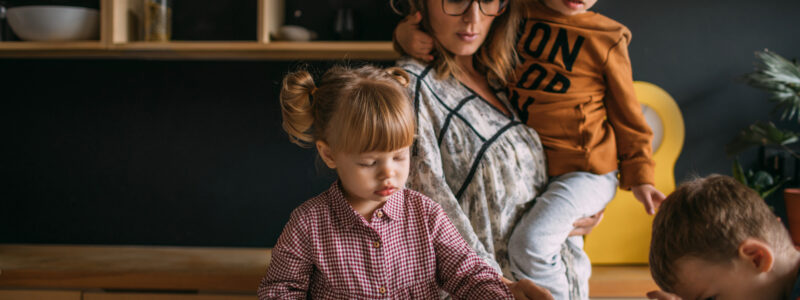 A woman and three children decorate biscuits in the kitchen.