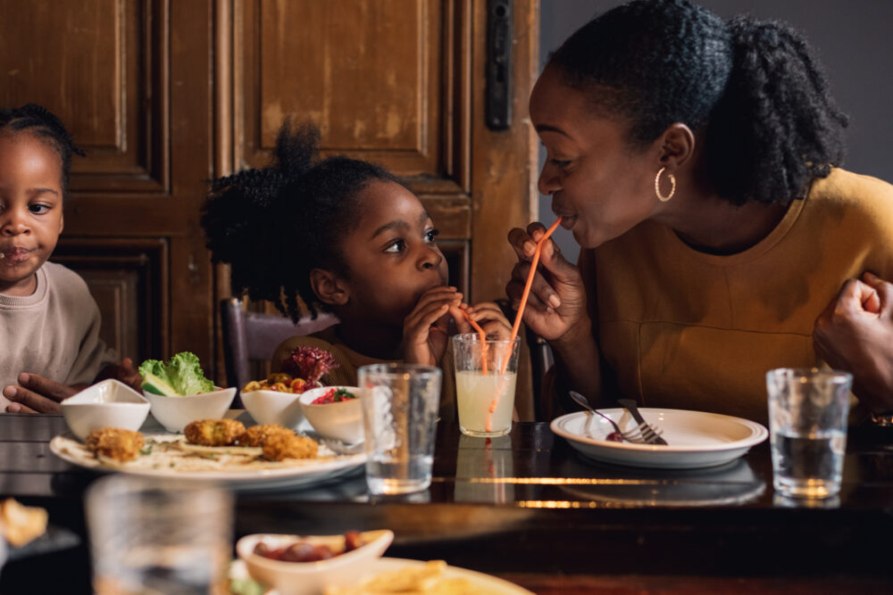 A woman and three children share drinks and food at a table.
