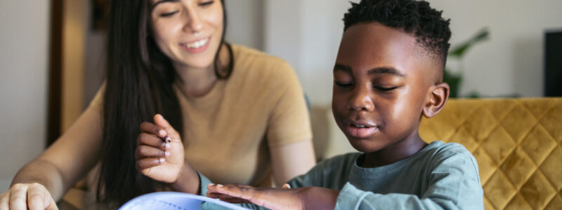 A woman helps a boy with his schoolwork.