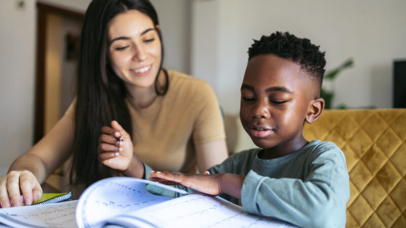 A woman helps a boy with his schoolwork.