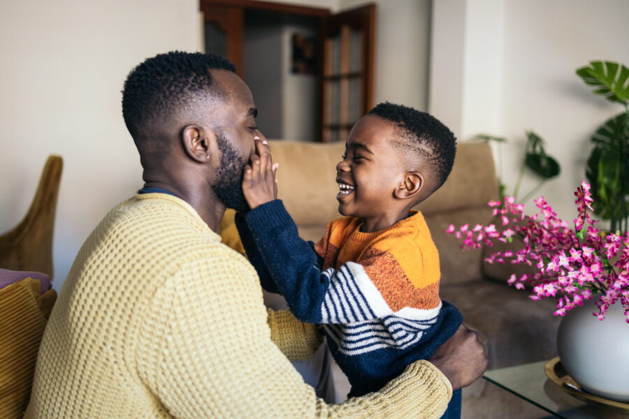 A man and a boy laugh together at home.