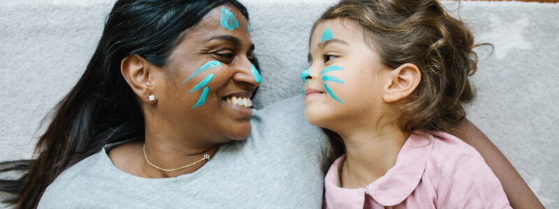 A woman and a girl lie together with matching face paint.