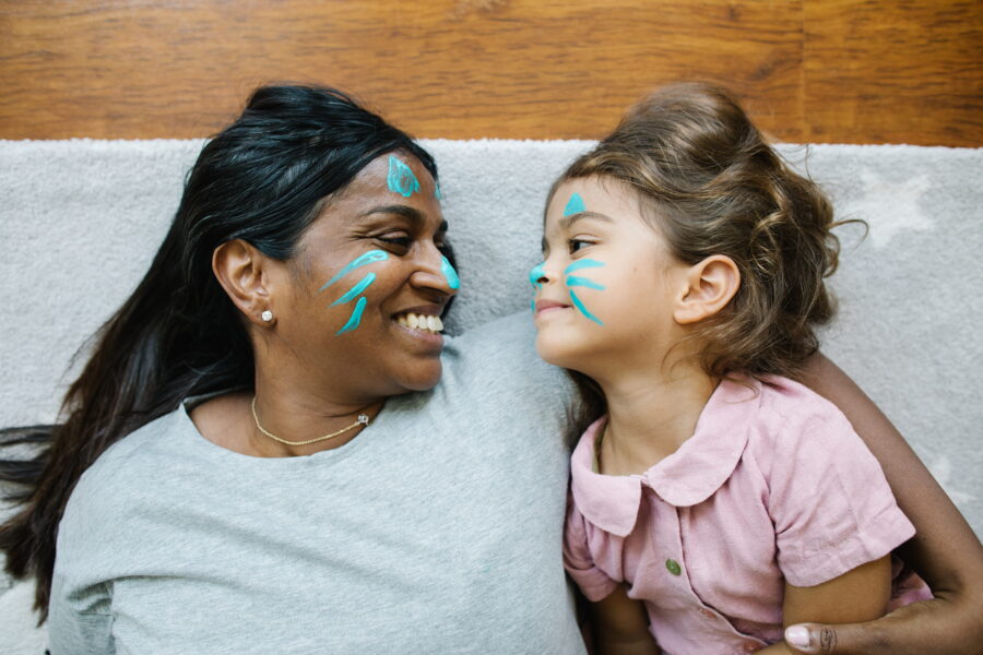 A woman and a girl lie together with matching face paint.