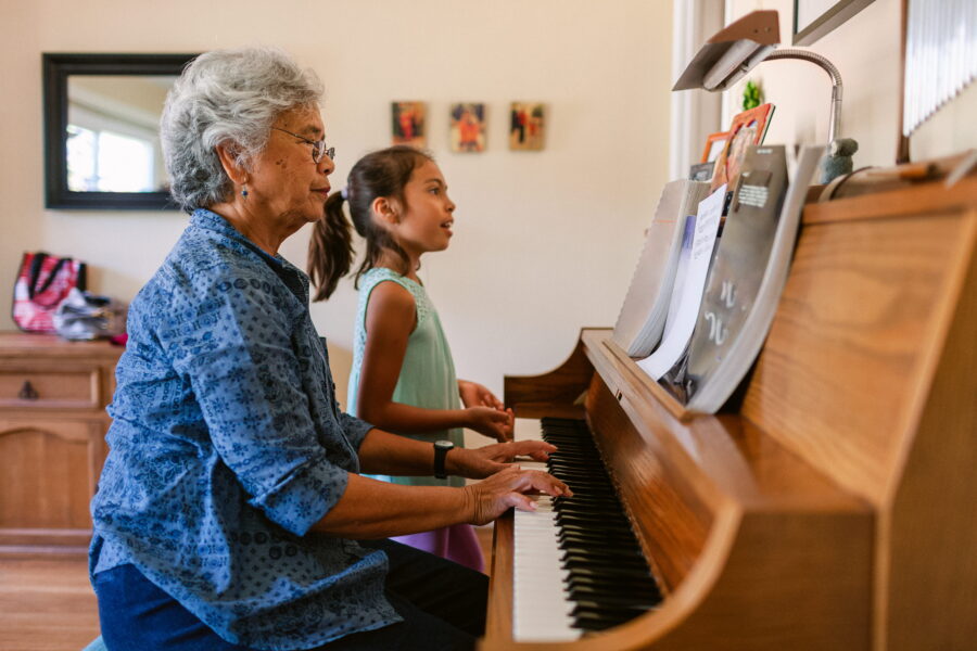 An older woman and a girl play piano together.